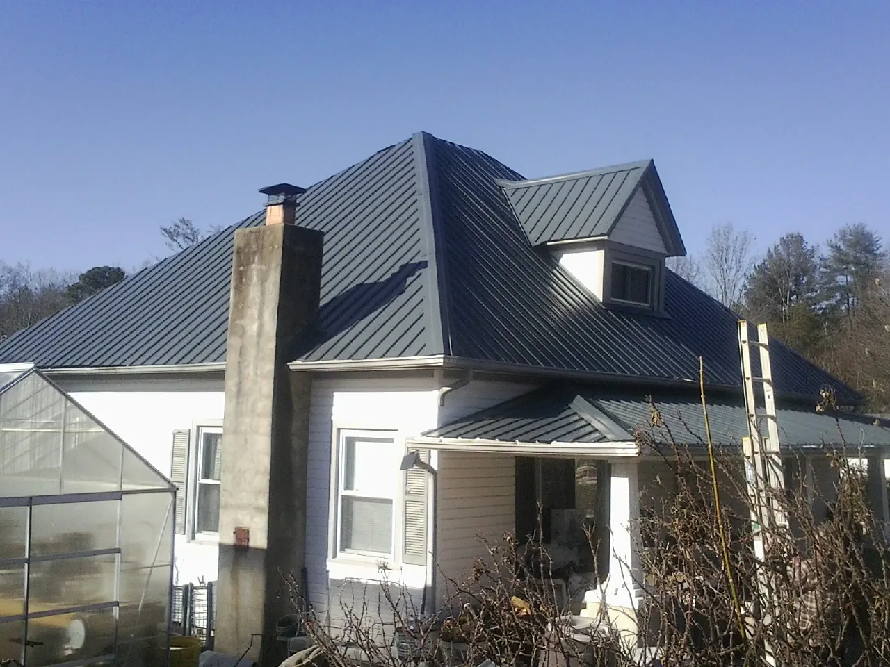 Dark blue standing seam metal roof on a white farmhouse with dormer — Slate & Tile Roof Repair by Roofing Brothers in Pleasant Hall