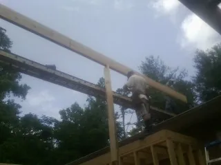 Carpenter setting a ridge beam over a new addition frame — Ice Dam Removal by Roofing Brothers in Pleasant Hall