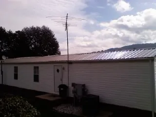 New metal roof on a single wide mobile home with a TV antenna in Pleasant Hall