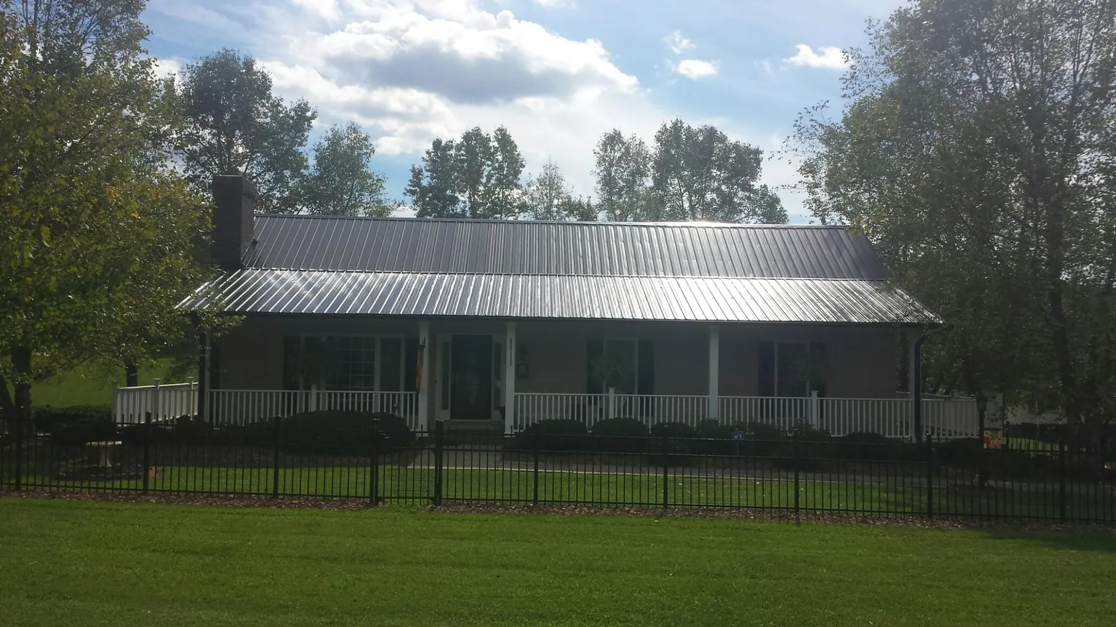 Gray metal roof on a brick ranch with a full width front porch — Gutter Guard Installation work by our crew in Pleasant Hall