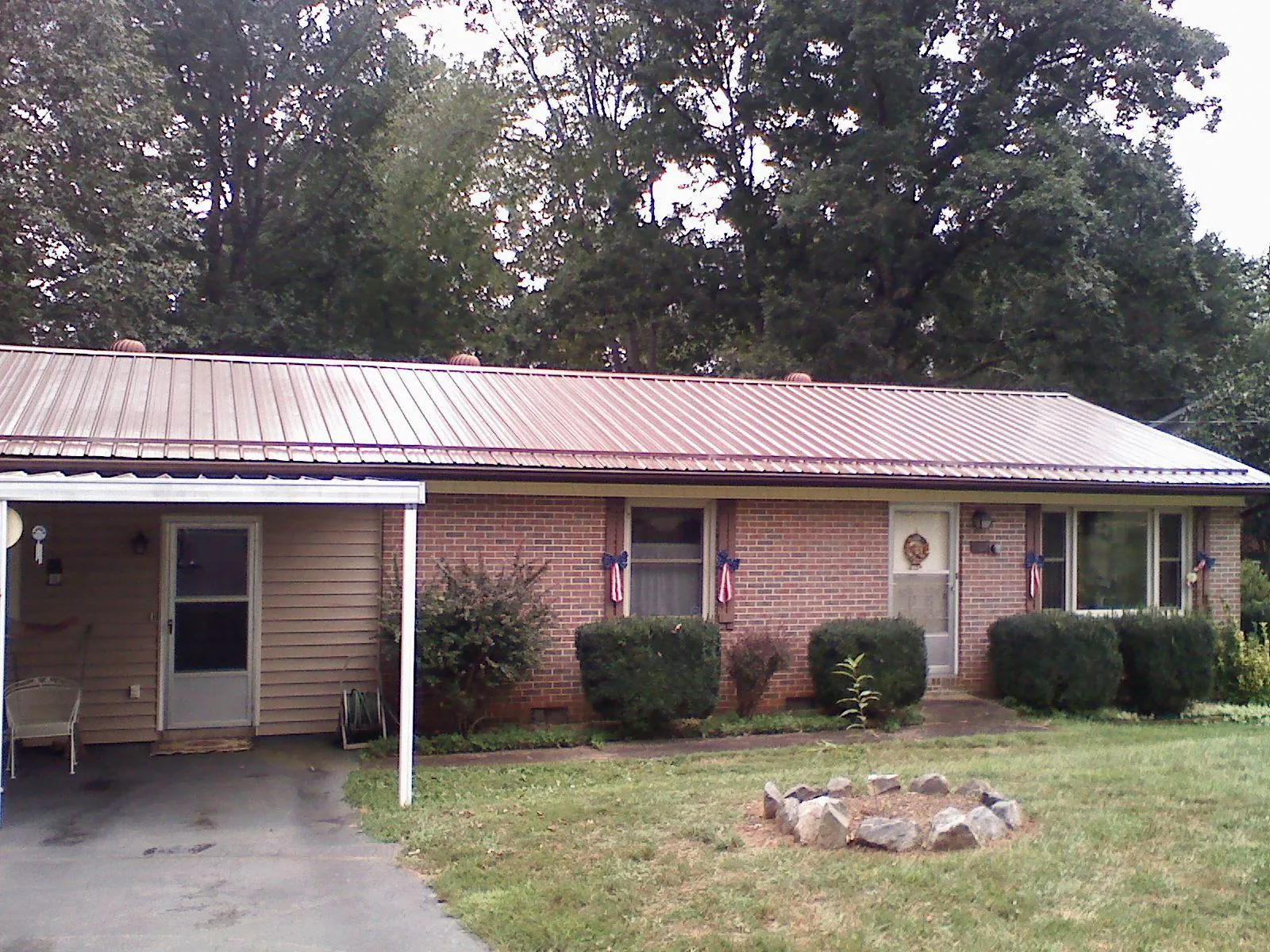Bronze metal roof and carport on a brick ranch home — Roof Repair work by our crew in Pleasant Hall