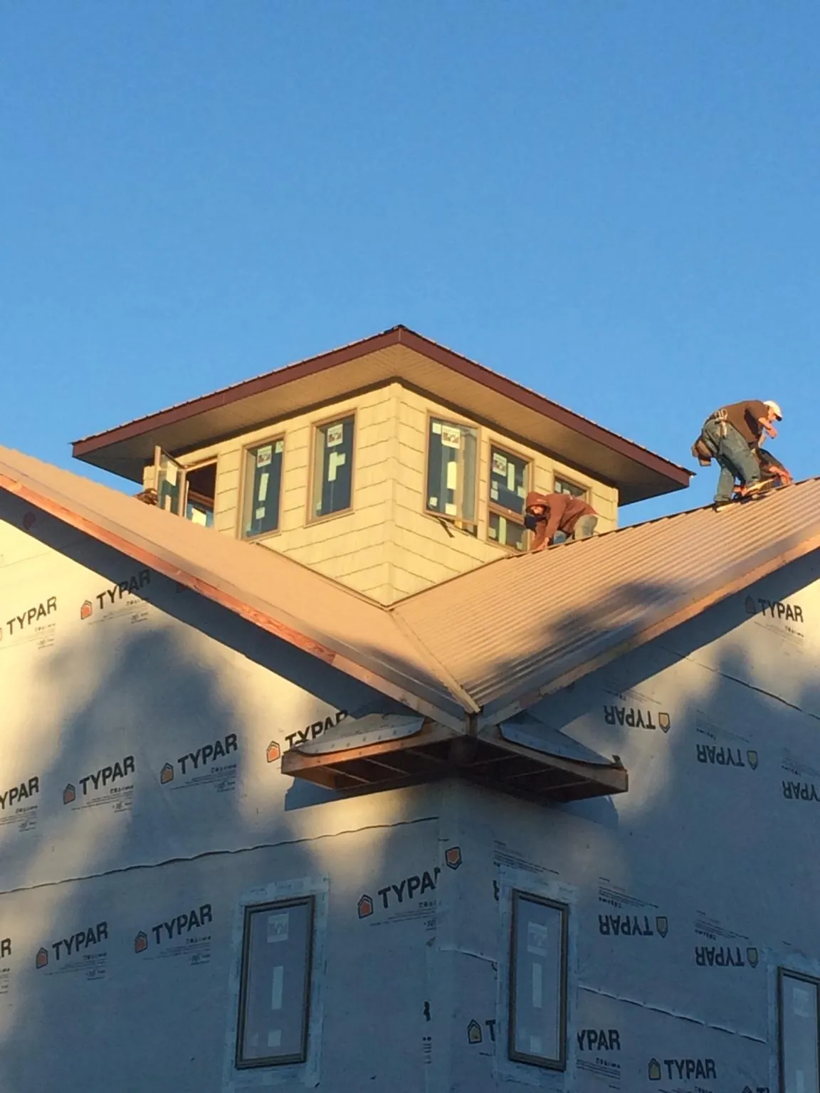 Roofers working around a rooftop cupola on a new metal roof at sunset — Roof Waterproofing in Pleasant Hall by Roofing Brothers